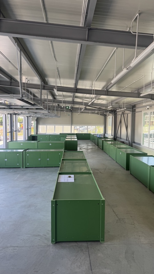 Interiorul Pieței Elitte din Chiajna, cu șiruri de tarabe metalice verzi și structura metalică a acoperișului